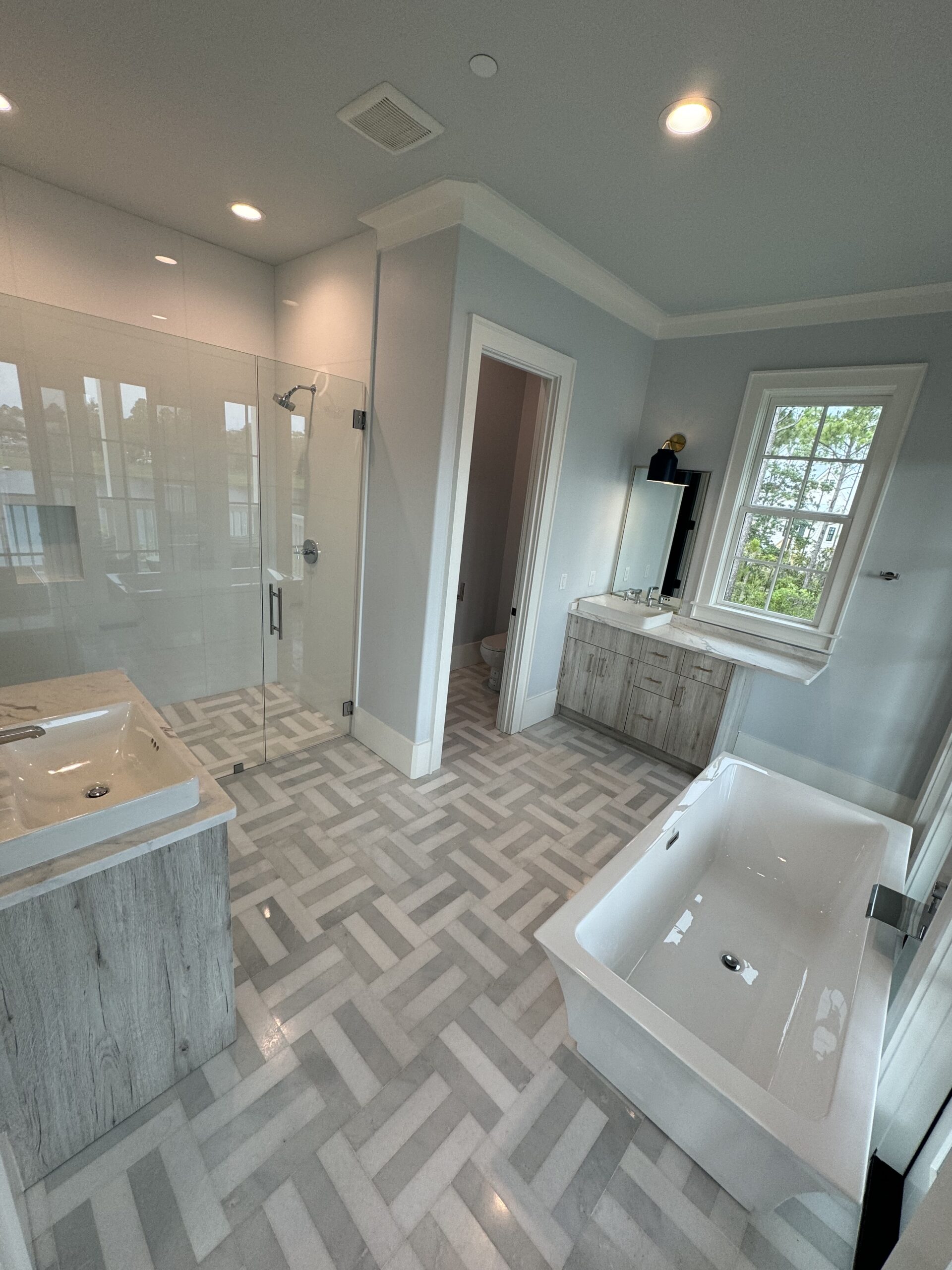 Finished bathroom remodel with walk-in glass shower, custom tile flooring, bathtub, vanity, and trim work by Alabaster Contracting Solutions in Cincinnati Ohio.