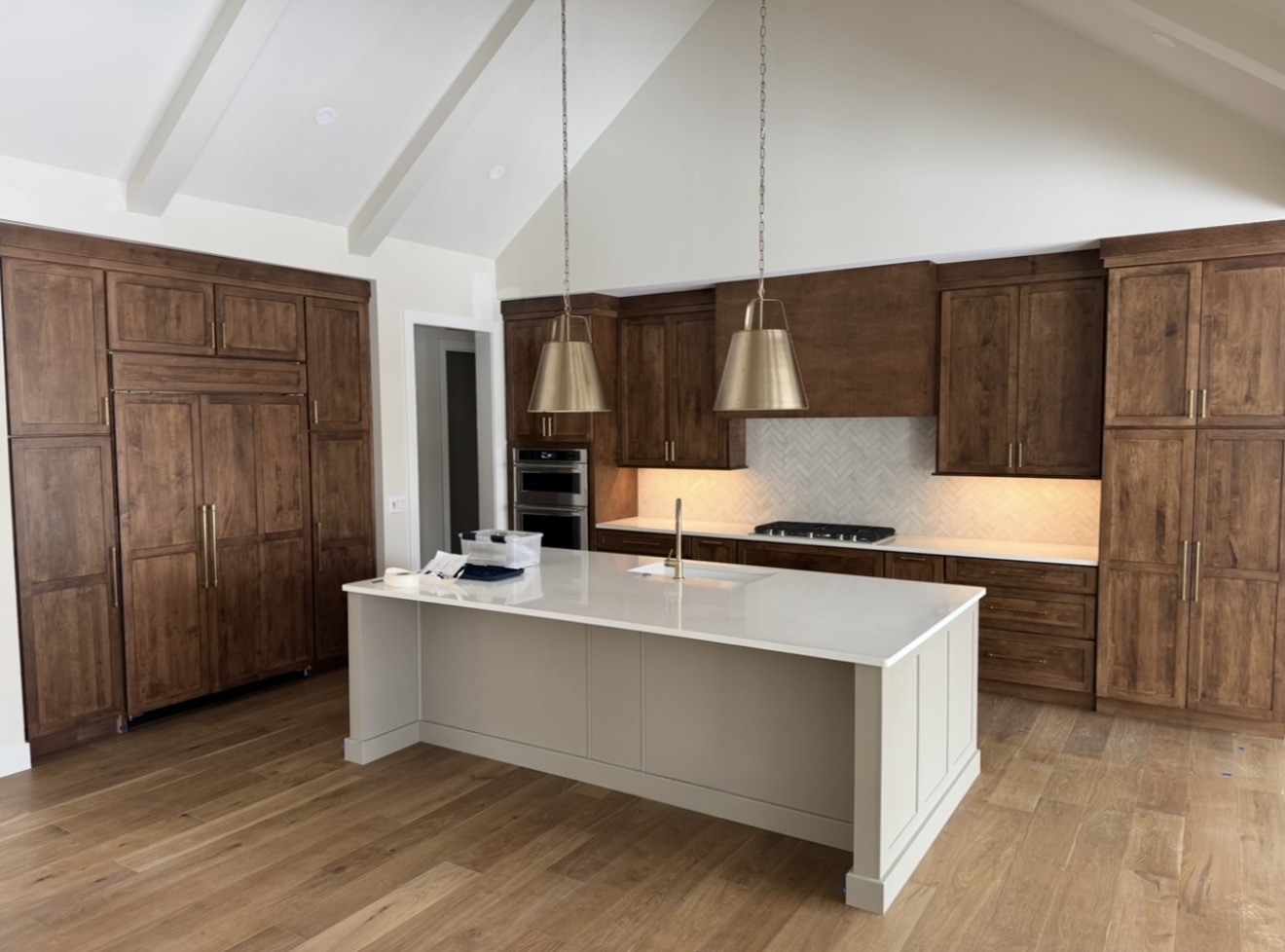 Finished kitchen remodel with custom wood cabinets, large island, quartz countertops, tile backsplash, and wood flooring by Alabaster Contracting Solutions in Cincinnati Ohio
