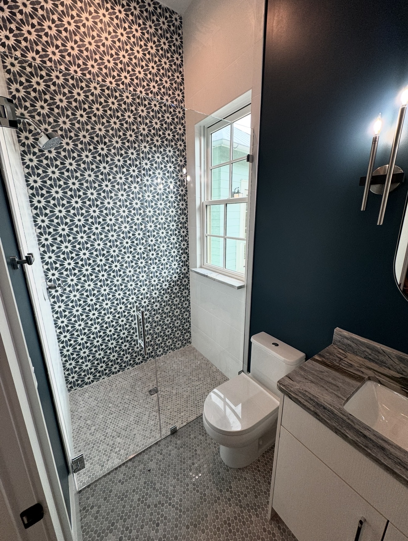 Custom tile walk-in shower remodel with glass shower door, patterned tile wall, tile floor, vanity, and bathroom finish work by Alabaster Contracting Solutions in Greater Cincinnati.