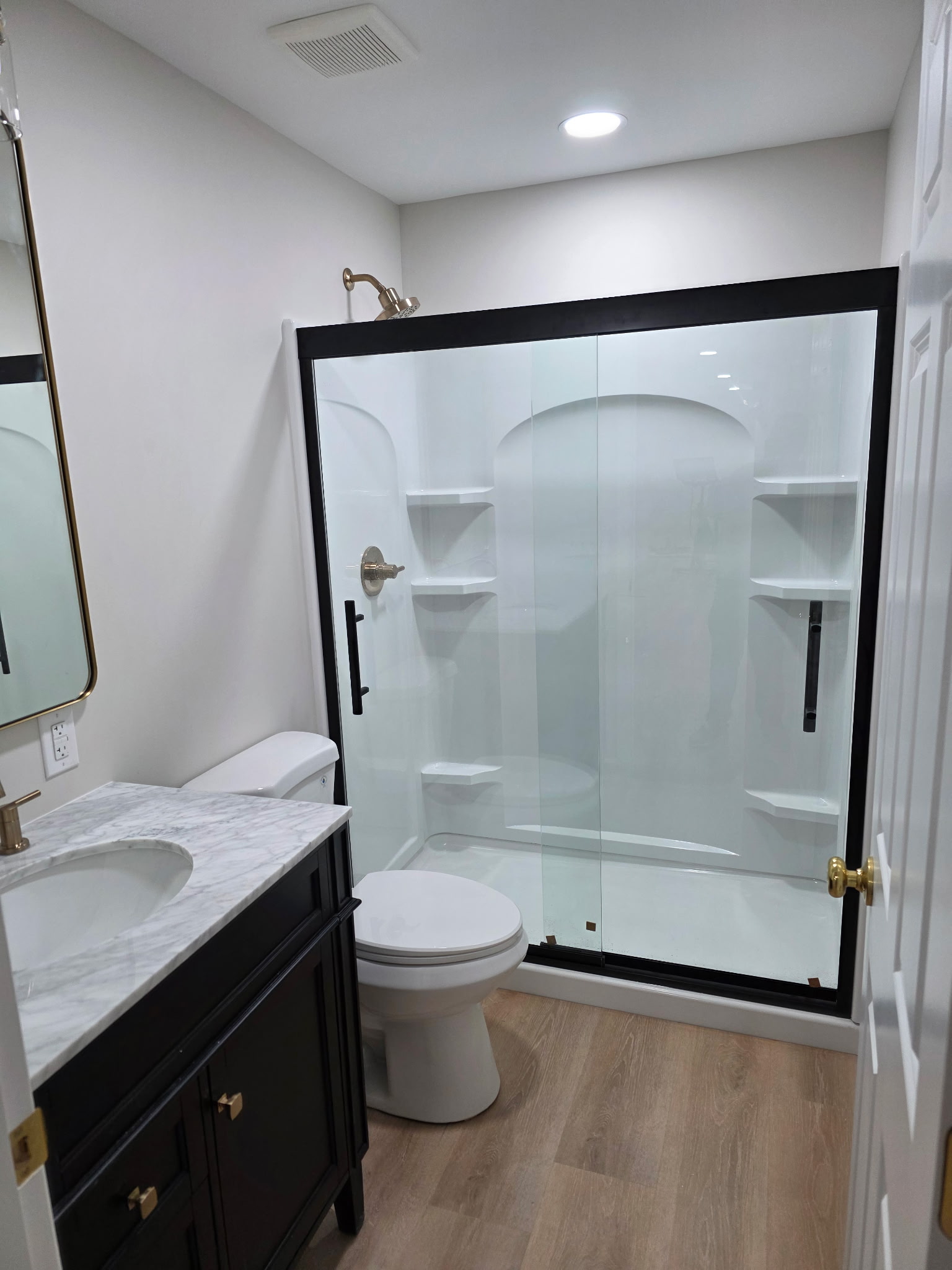 Bathroom shower update with glass shower door, vanity, flooring, lighting, plumbing fixtures, and clean finish work by Alabaster Contracting Solutions
