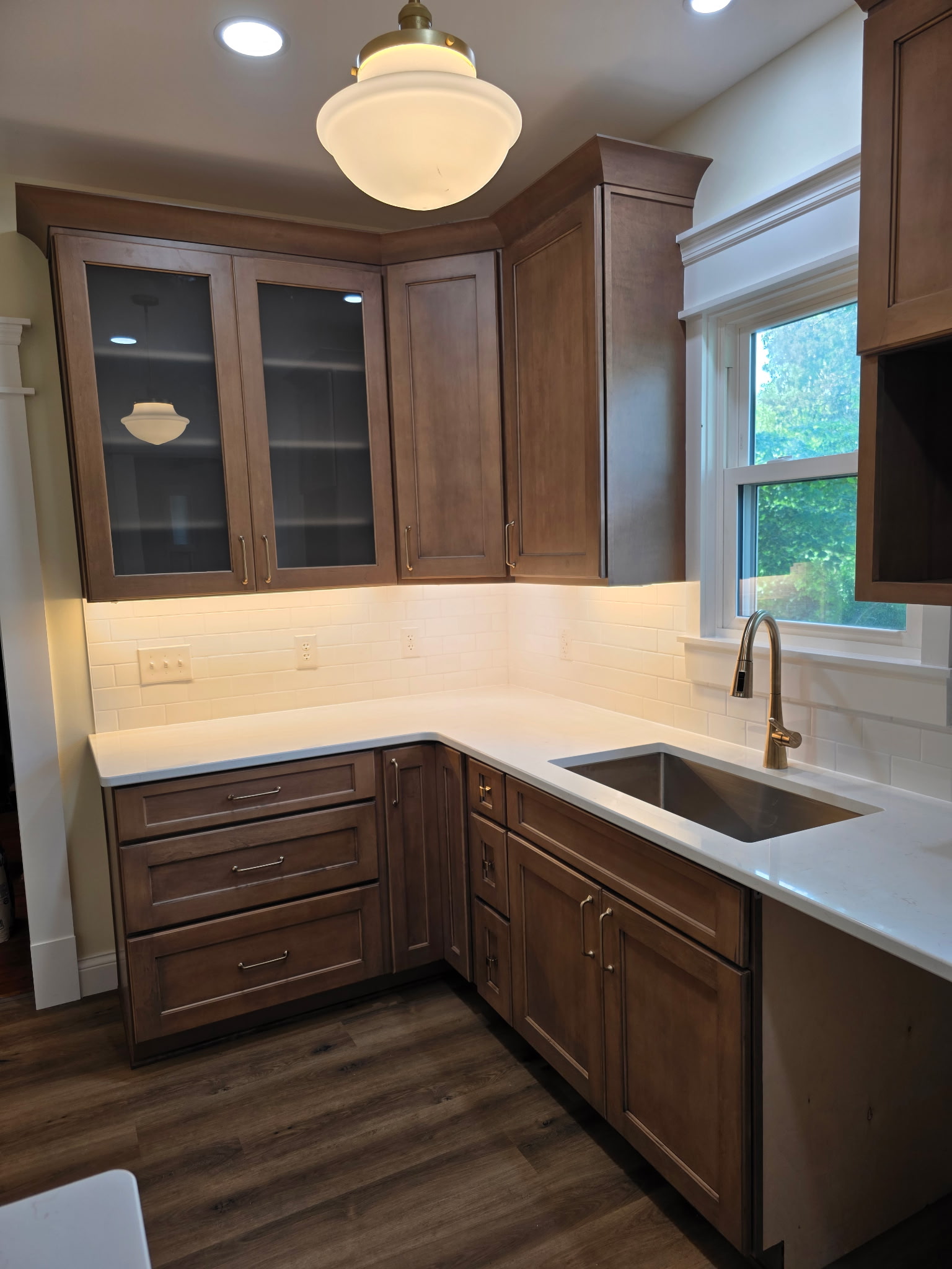 Kitchen remodel detail with custom cabinetry, sink area, tile backsplash, window trim, lighting, and finish carpentry by Alabaster Contracting Solutions in Southwest Ohio