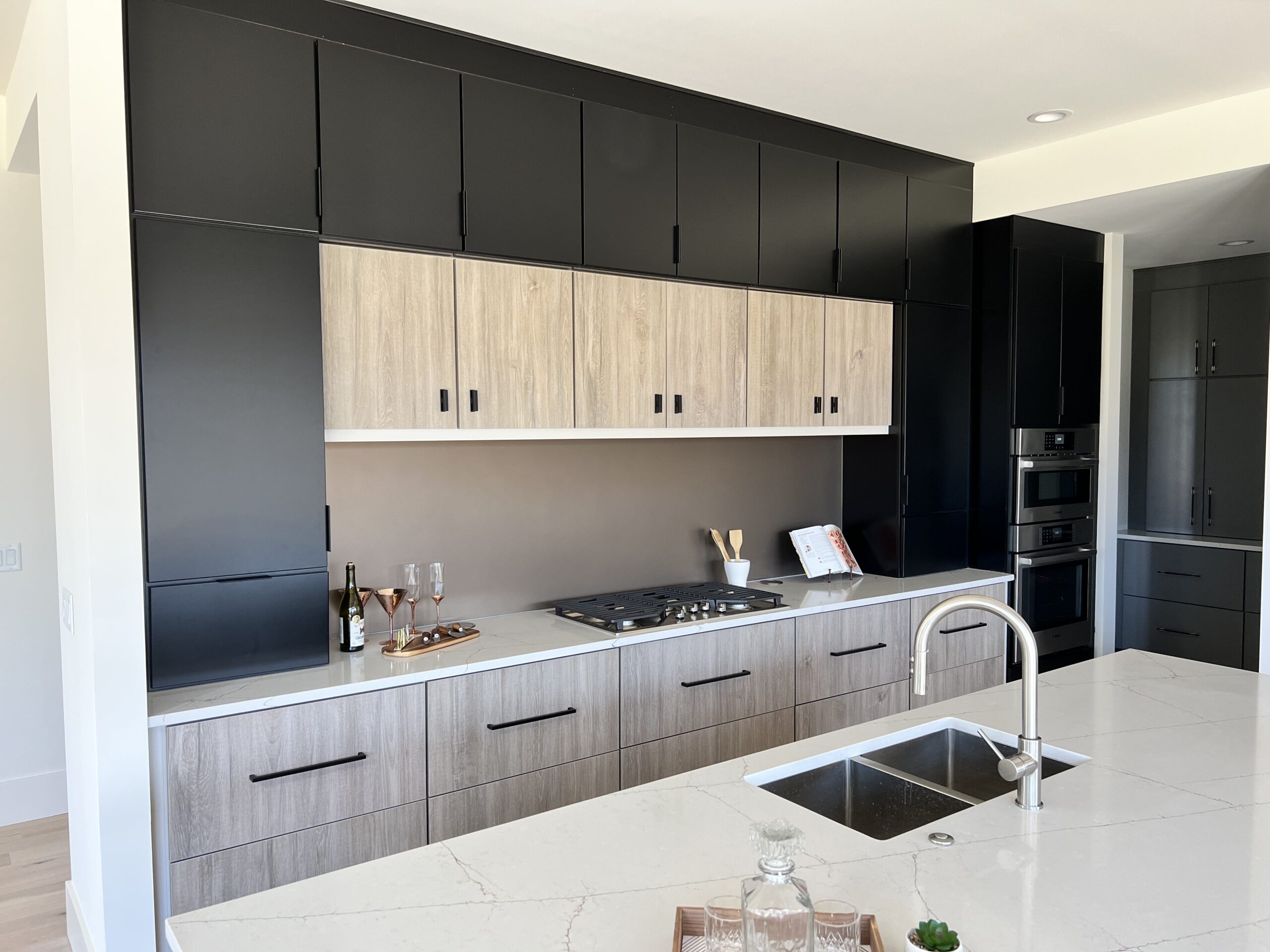 Modern kitchen remodel with two-tone custom cabinets, quartz countertops, island sink, built-in appliances, and finish work by Alabaster Contracting Solutions in Greater Cincinnati